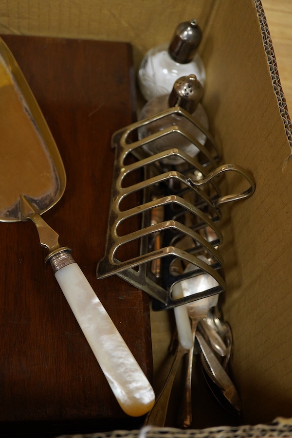 A cased set of twelve pairs of mother of pearl handled plated dessert eaters and a quantity of assorted plated items including a toastrack, a pair of mounted glass condiments, crumb scoop and miscellaneous flatware.